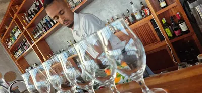 a man standing behind a bar with several wine glasses at Cabo Verde Beach Sport Resort in Porto Novo