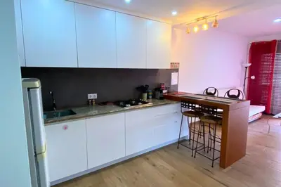 a kitchen with white cabinets and a wooden floor at A Baia do Fortim in Mindelo