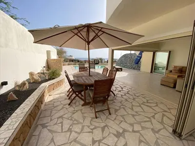 a table and chairs with an umbrella on a patio at Surf House - Your Exclusive Getaway in Palmeira