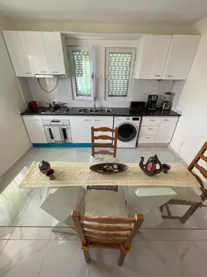 a kitchen with white cabinets and a table and chairs at La maison paisible in Malveira