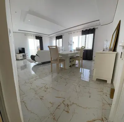 a living room with a table and chairs on a marble floor at La maison paisible in Malveira