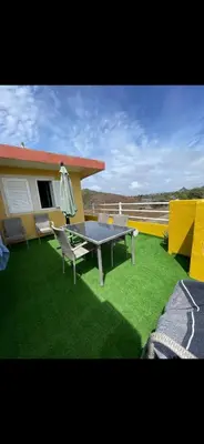 a patio with a table and a chair on the grass at La maison paisible in Malveira