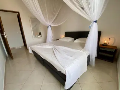 a bedroom with a bed with white curtains at Estrela do Mar - Rooftop Ocean View in Santa Maria