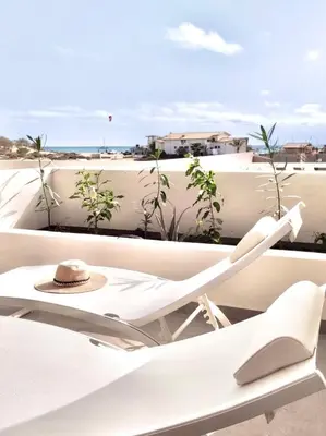 a white chair on a balcony with a hat at Stylish Lagoon Paradise Apartment Boa Vista in Sal Rei