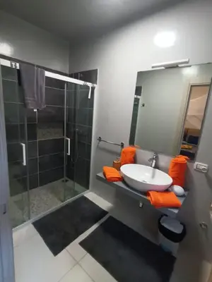 a bathroom with a sink and a shower with orange towels at Ocean Dream BeachHouse Boa Vista in Sal Rei