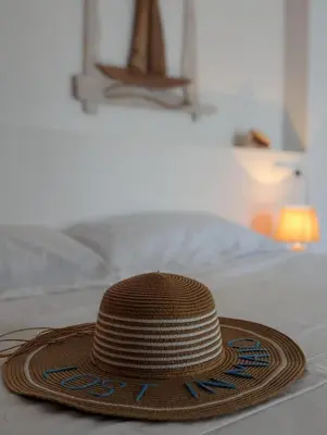 a straw hat sitting on top of a bed at Vila de Matiz in Vila do Maio