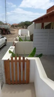 a white building with a fence next to a car at Vila de Matiz in Vila do Maio