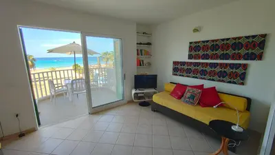 a living room with a couch and a balcony with the ocean at Albis Harena - Leme Bedje Residence in Santa Maria
