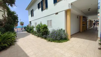 a white building with a courtyard with purple flowers at Albis Harena - Leme Bedje Residence in Santa Maria