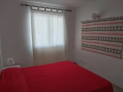 a bedroom with a red bed and a window at Albis Harena - Leme Bedje Residence in Santa Maria