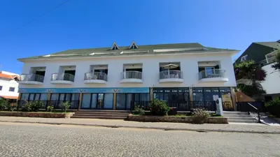 a white building with balconies on a street at Albis Harena - Leme Bedje Residence in Santa Maria