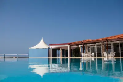 a swimming pool with chairs and a building at Murdeira Village in Beirona