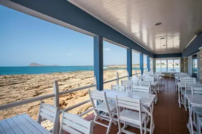 a row of white tables and chairs on the beach at Murdeira Village in Beirona