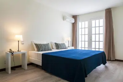 a bedroom with a large bed with a blue blanket at Murdeira Village in Beirona