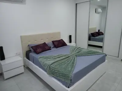 a white bedroom with a large bed with a blanket at Appartement standing praia in Praia