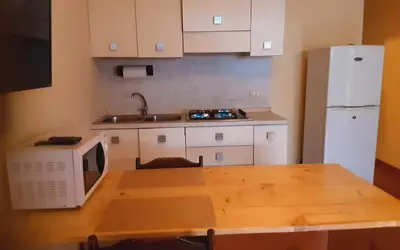 a kitchen with a table with a microwave and a refrigerator at Padaria Portuguesa, with porch facing the street in Santa Maria