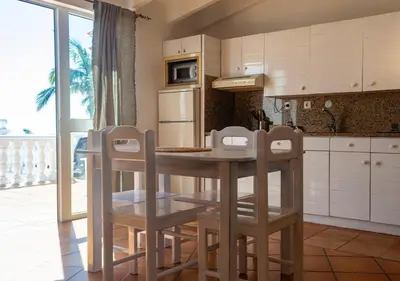 a kitchen with a table and chairs and a refrigerator at Vista Mar - Seafront Holiday Apartments in Santa Maria