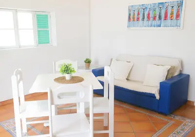 a living room with a blue couch and a table at Vista Mar - Seafront Holiday Apartments in Santa Maria