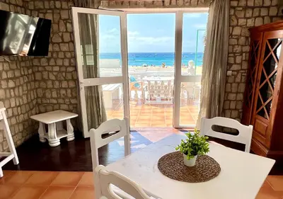 a dining room with a table and a view of the ocean at Vista Mar - Seafront Holiday Apartments in Santa Maria
