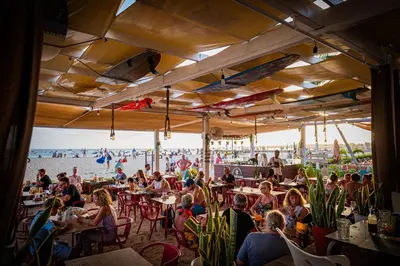 a group of people sitting at a restaurant on the beach at Vista Mar - Seafront Holiday Apartments in Santa Maria