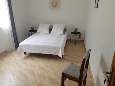 a bedroom with a white bed and a chair at Residencia Solimar in Ponta do Sol