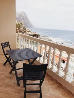 a table and chairs on a balcony with the ocean at Residencia Solimar in Ponta do Sol