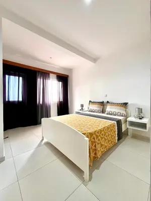 a bedroom with a large bed with a yellow blanket at Oásis de retour in Ponta do Sol