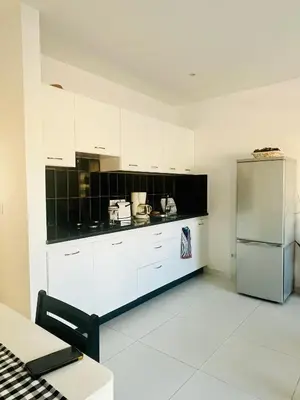 a kitchen with white cabinets and a stainless steel refrigerator at Oásis de retour in Ponta do Sol