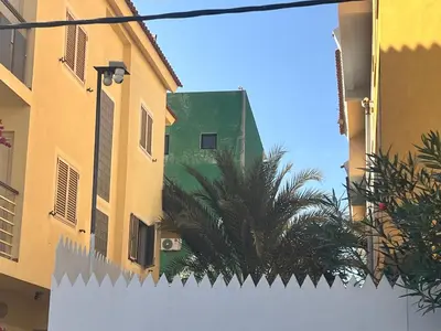 a white fence in front of buildings and a palm tree at sweet single in Santa Maria