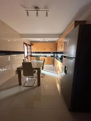 a large kitchen with a table and a refrigerator at Casa Lima in Mindelo