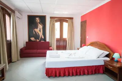 a red bedroom with a white bed and a red couch at Royal Mindelo Suite in Mindelo