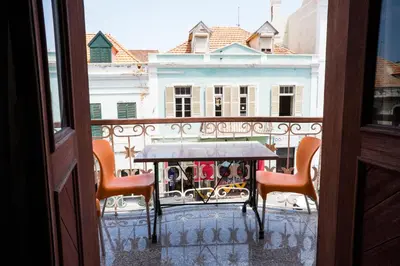a balcony with a table and chairs and a building at Royal Mindelo Suite in Mindelo