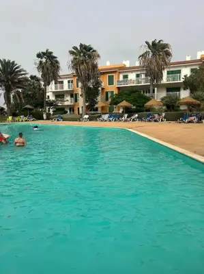a large blue swimming pool next to a beach at Vida boa é no Vila Verde Sal in Santa Maria