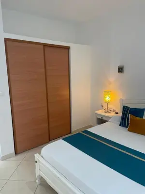 a bedroom with a large bed with a wooden door at Casa Nela grand balcon vitré in Tarrafal