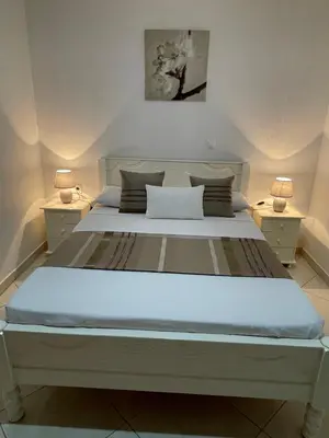 a large white bed with two nightstands and two lamps at Casa Nela grand balcon vitré in Tarrafal