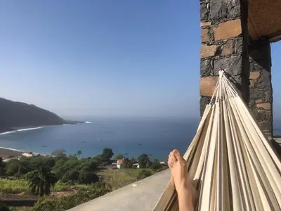a person sitting on a balcony looking at the ocean at Casa Saúde in Seladinha