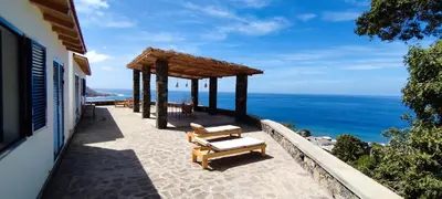 a patio with two benches and a view of the ocean at Casa Saúde in Seladinha