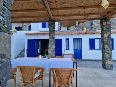 a table with chairs on a patio with blue doors at Casa Saúde in Seladinha