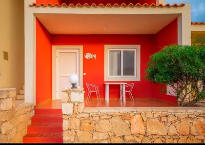 a red house with a table and a window at Garoupa Stella Maris Apartamento N10 in Vila do Maio