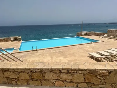 a swimming pool with chairs and the ocean in the background at Garoupa Stella Maris Apartamento N10 in Vila do Maio