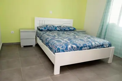 a bedroom with a bed with a blue and white comforter at FADIAS Quartos - Rooms in Ribeira Grande