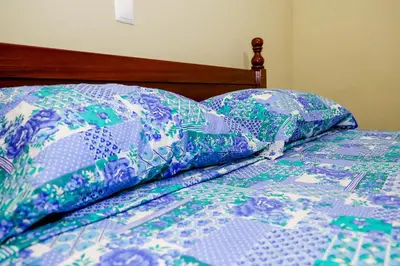 a bed with a blue and green quilt on it at FADIAS Quartos - Rooms in Ribeira Grande