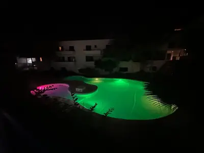 a green pool at night with a building in the background at FantaSea Apartment Leme Bedje in Santa Maria