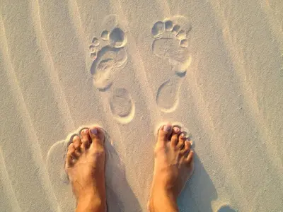 a person standing on the beach with footprints in the sand at Attico Residence Costa do Sol in Sal Rei