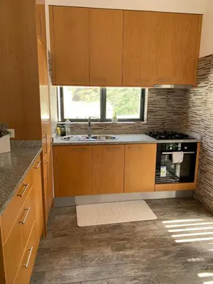 a kitchen with wooden cabinets and a sink and a window at Apartamentos Modernos Santo Antão in Ribeira Grande