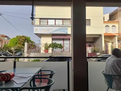 a man sitting at a table on a balcony at Elite Residences MVT in Praia