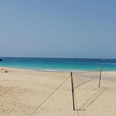a volleyball net on a beach with the ocean at Pensão Big Game Maio Vila do Maio in Vila do Maio