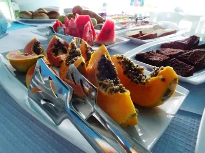 a plate of fruit on a table with tongs at Pensão Big Game Maio Vila do Maio in Vila do Maio