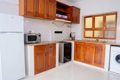 a kitchen with wooden cabinets and a white refrigerator at Bungavília house, Palmarejo in Praia