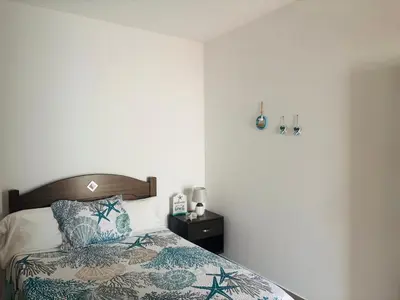 a bedroom with a bed with a pillow and a nightstand at Techas Stylish 2-Bedroom 8 min to Beach in Tarrafal